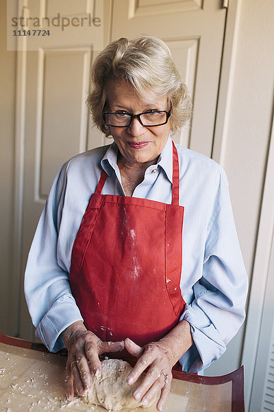 Ältere Frau formt Teig in der Küche