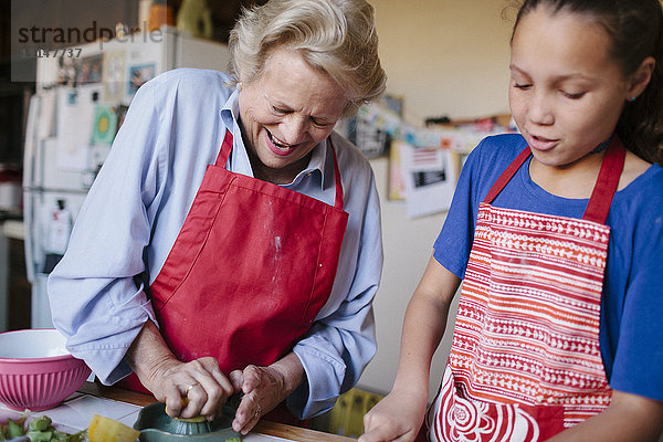 Großmutter und Enkelin beim Auspressen von Saft in der Küche