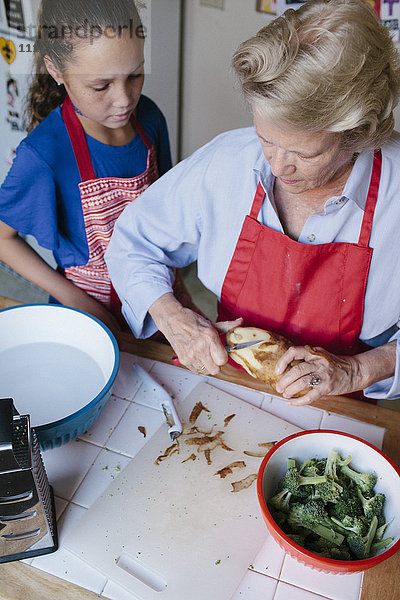 Großmutter und Enkelin beim Kartoffelschälen in der Küche