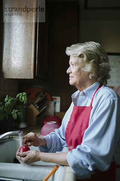 Ältere Frau wäscht Geschirr in der Spüle