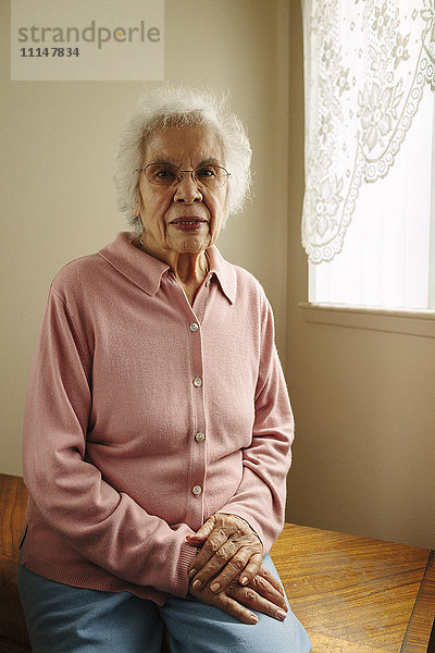 Ältere gemischtrassige Frau sitzt auf einem Tisch