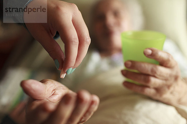Enkelin gibt Großmutter Medikamente im Bett