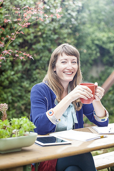 Gemischtrassige Geschäftsfrau trinkt Kaffee im Hinterhof
