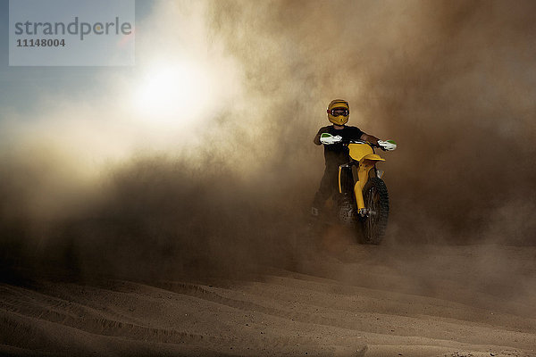 Kaukasischer Mann fährt Dirt Bike in Staubwolke