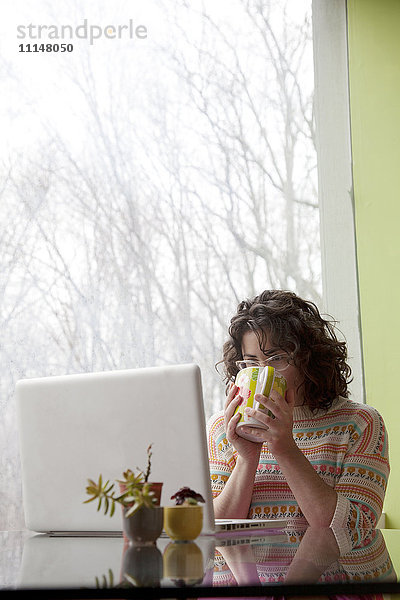 Kaukasische Geschäftsfrau trinkt Kaffee am Schreibtisch