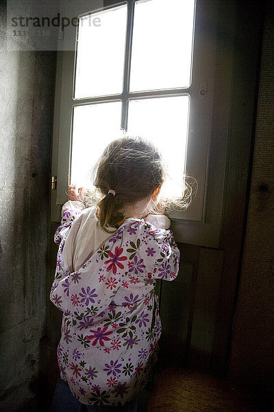 Kaukasisches Mädchen schaut aus dem Fenster