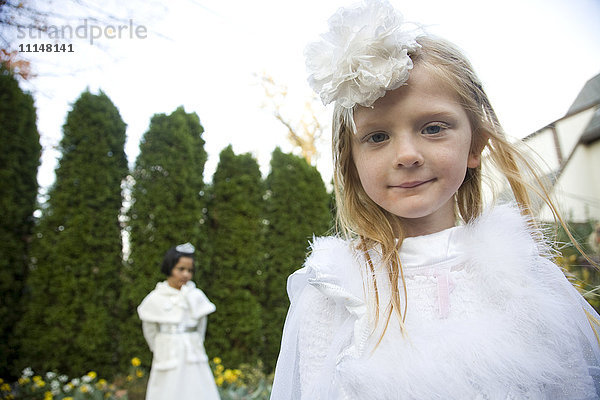 Kaukasische Mädchen in weißen Kleidern gehen im Garten