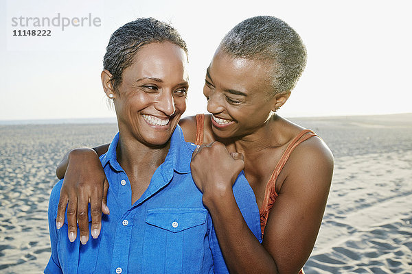 Ältere schwarze Frauen umarmen sich am Strand