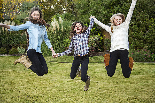 Kaukasische Teenager-Mädchen springen vor Freude im Hinterhof