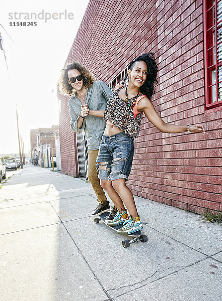 Paar fährt Skateboard auf einer Straße in der Stadt
