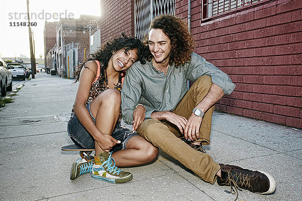 Paar sitzt auf einem Skateboard auf einer Straße in der Stadt
