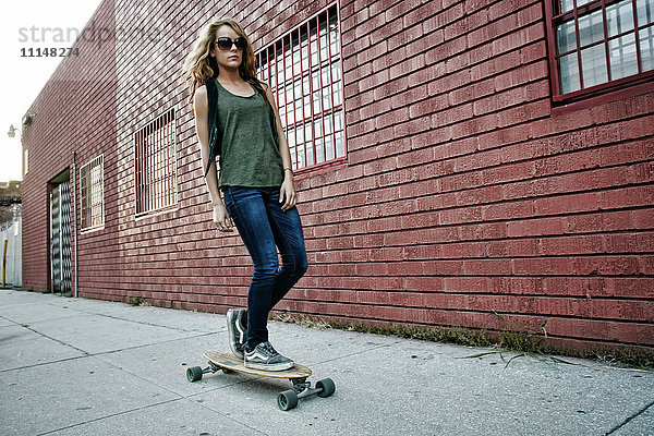Gemischtrassige Frau fährt Skateboard auf einer Straße in der Stadt