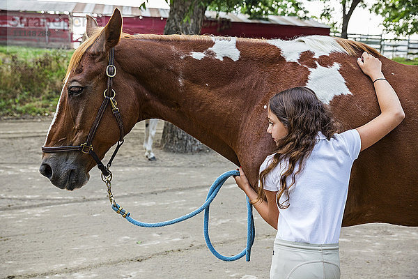 Teenager-Mädchen umarmt Pferd auf Ranch