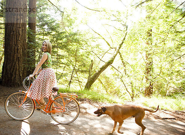 Gemischtrassige Frau fährt Fahrrad mit Hund