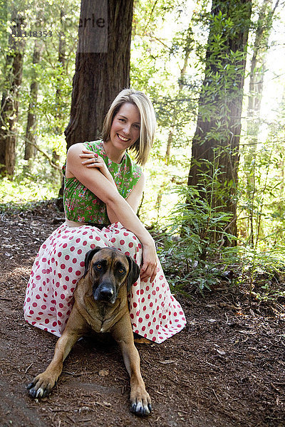 Gemischtrassige Frau und Hund im Wald