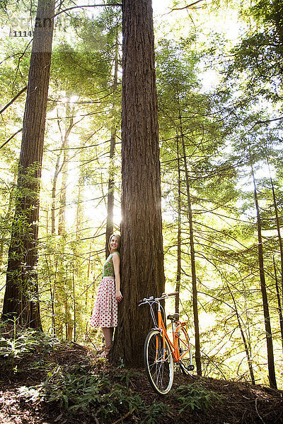 Gemischtrassige Frau und Fahrrad im Wald