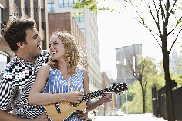 Kaukasisches Paar spielt Ukulele in der Stadt