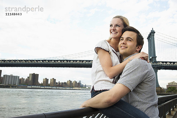 Kaukasisches Paar umarmt sich unter der Brooklyn Bridge  Brooklyn  New York  Vereinigte Staaten