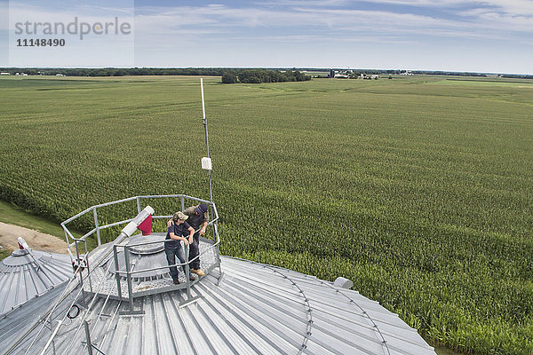 Kaukasischer Bauer und Sohn bewundern den Bauernhof vom Silo aus