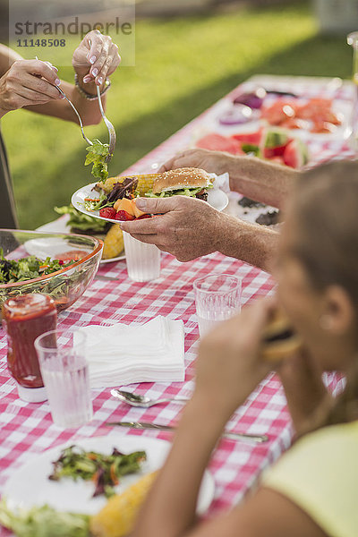 Kaukasische Familie beim Essen im Hinterhof