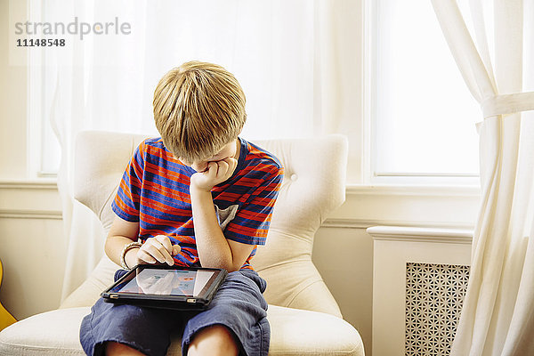 Kaukasischer Junge benutzt digitales Tablet im Wohnzimmer