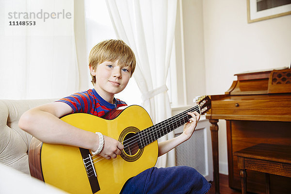 Kaukasischer Junge spielt Gitarre im Wohnzimmer