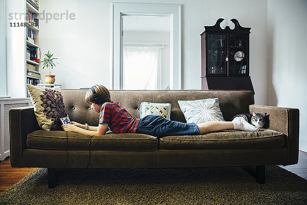 Kaukasischer Junge mit digitalem Tablet auf dem Sofa