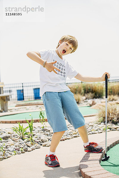 Kaukasischer Junge spielt Minigolf auf dem Platz