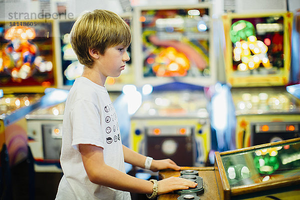 Kaukasischer Junge spielt Videospiel in einer Spielhalle