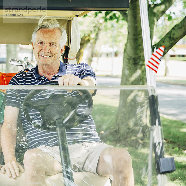 Älterer kaukasischer Mann fährt Golfwagen