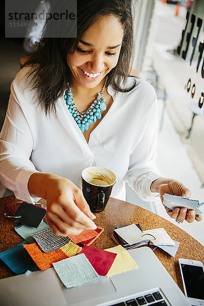 Geschäftsfrau begutachtet Stoffmuster in einem Cafe