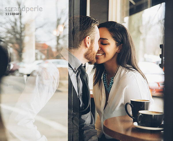 Lächelndes Paar  das sich im Café küsst