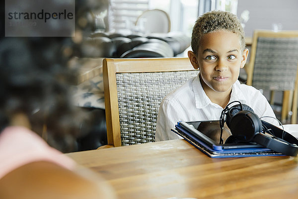 Junge mit digitalem Tablet im Restaurant sitzend