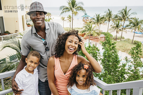 Familie lächelnd auf den Stufen mit Blick auf den Strand