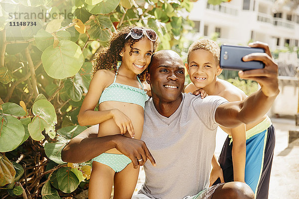 Vater und Kinder nehmen Selfie mit Handy im Freien