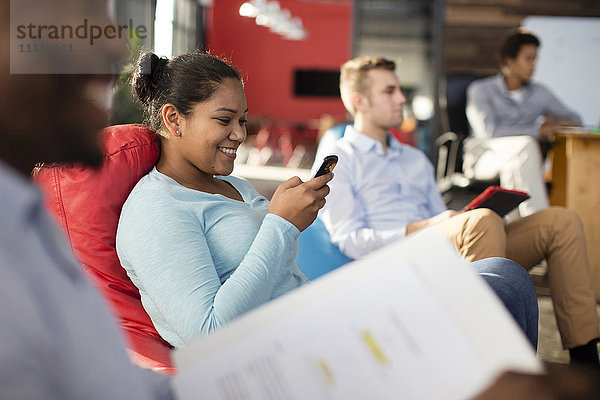 Geschäftsfrau benutzt Mobiltelefon in Bürolounge