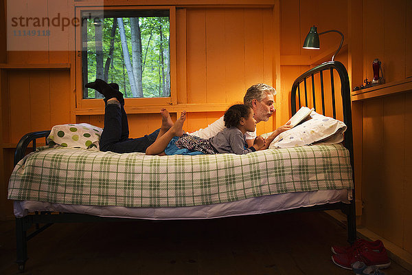 Vater und Tochter lesen auf dem Bett