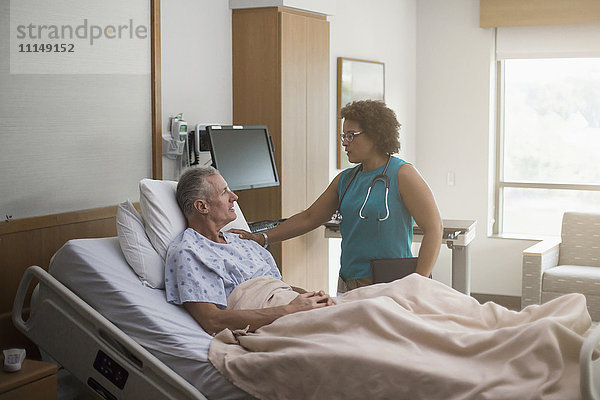 Arzt spricht mit Patient im Krankenhauszimmer
