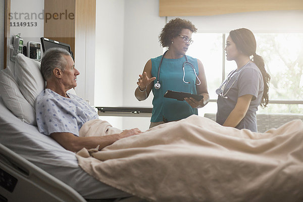 Arzt und Krankenschwester mit Patient im Krankenhauszimmer