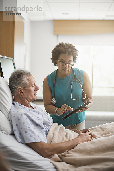 Arzt benutzt digitales Tablet mit Patient