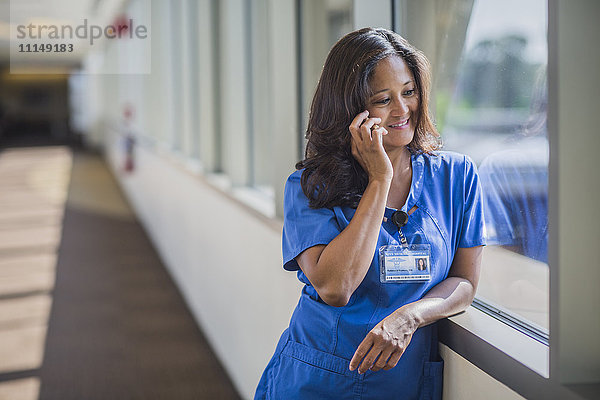 Philippinische Krankenschwester im Gespräch mit einem Handy