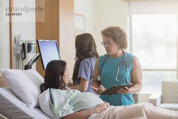 Arzt spricht mit schwangerer Patientin im Krankenhauszimmer