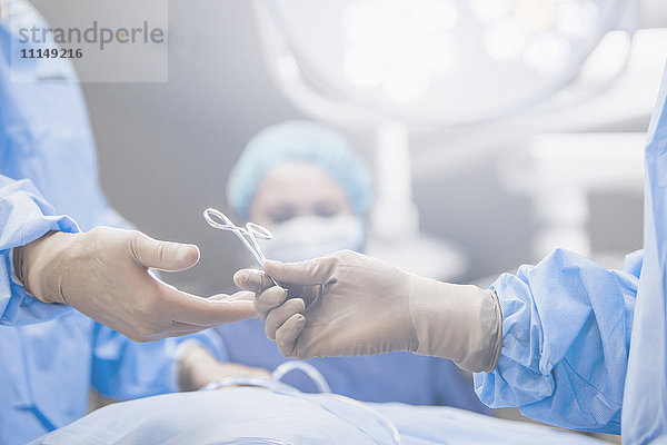 Chirurgen reichen Zangen im Operationssaal