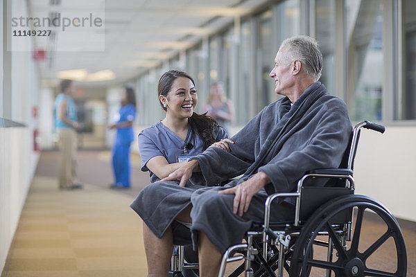 Krankenschwester spricht mit Patient im Rollstuhl