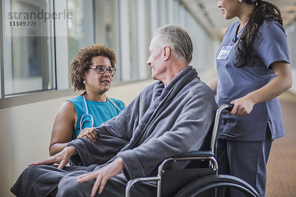 Arzt spricht mit Patient im Rollstuhl