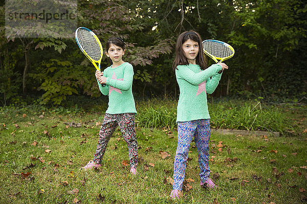 Zwillingsschwestern spielen Tennis im Gras