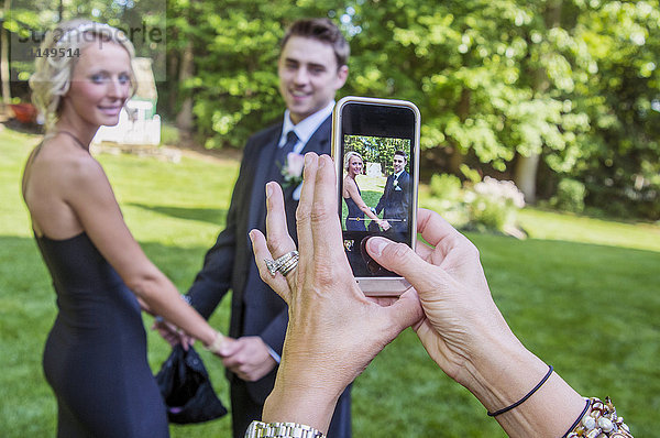 Frau fotografiert Paar mit ihrem Handy