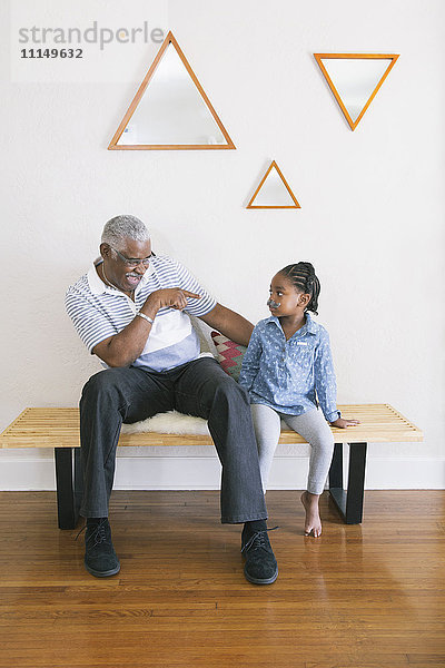 Afroamerikanischer Großvater zeigt auf seine Enkelin auf einer Bank
