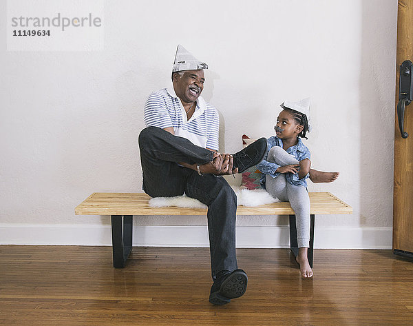 Afroamerikanischer Großvater und Enkelin spielen auf einer Bank