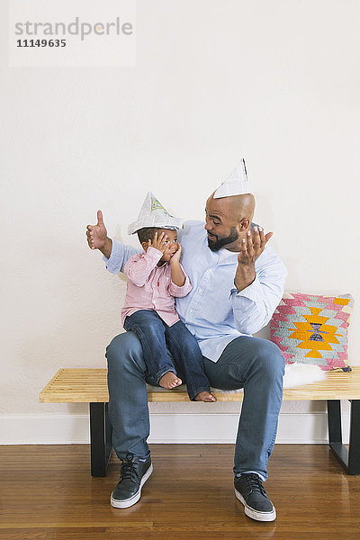 Afroamerikanischer Vater und Sohn spielen auf einer Bank